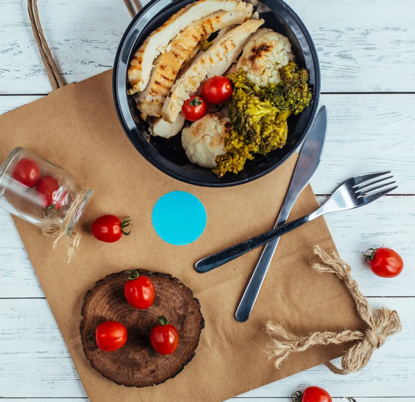 Жареная курица с брокколи и помидорами на деревянной доске.